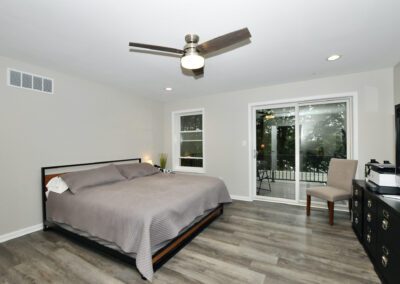 Grey bed and celling fan in a room