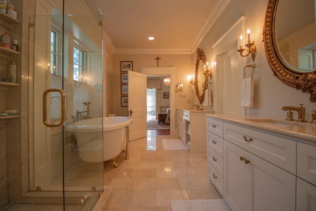 Luxurious bathroom featuring a glass-enclosed shower, a freestanding bathtub, elegant cabinetry, ornate mirrors, and warm ambient lighting.